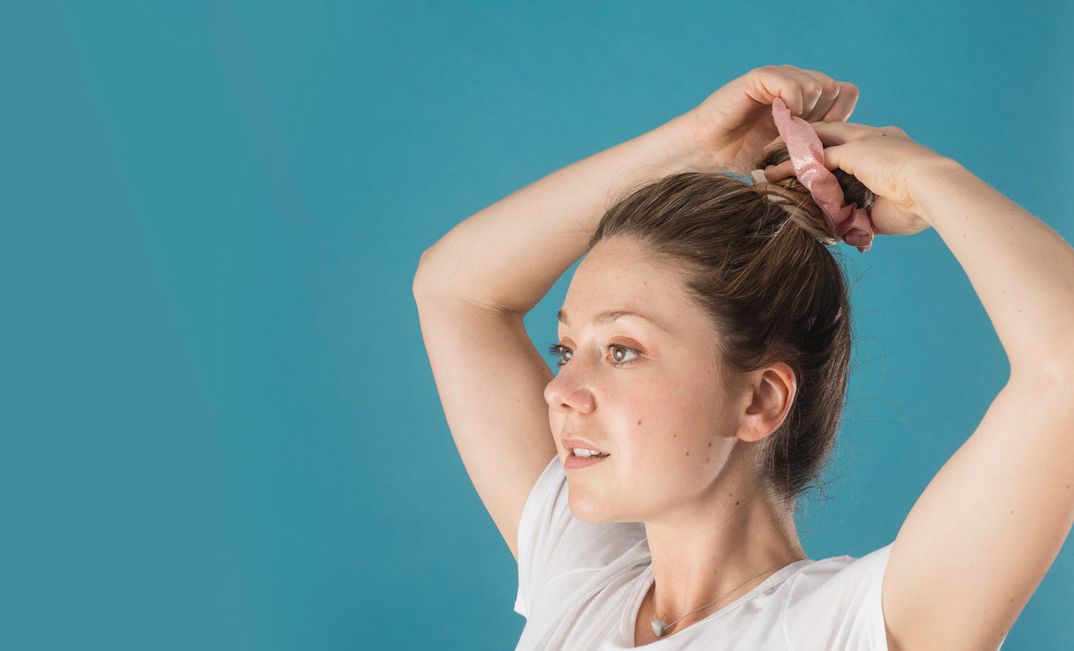 Femme attachant ses cheveux avec un chouchou rose