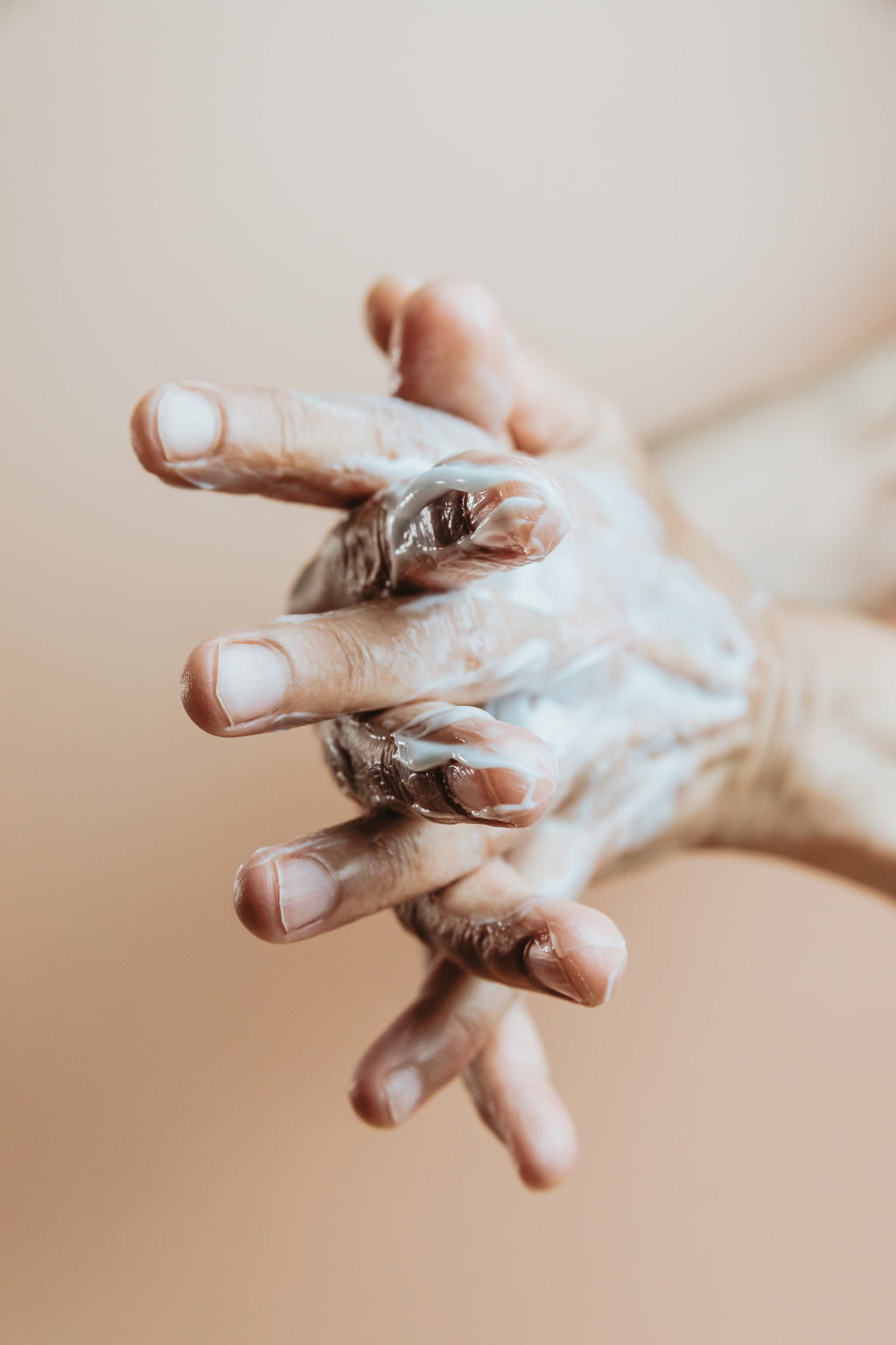 Mains appliquant un lait corps sur fond beige