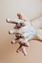 Mains appliquant un lait corps sur fond beige