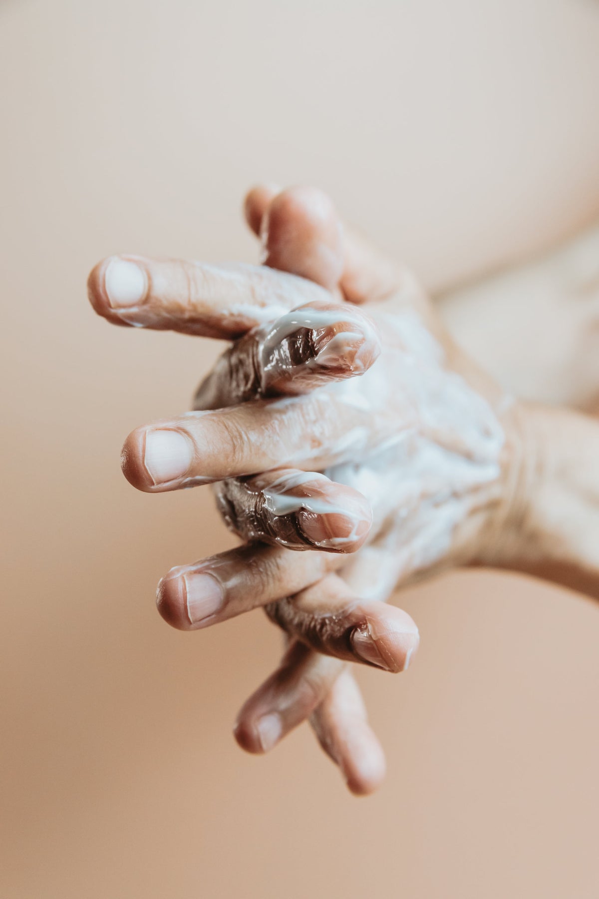 Mains appliquant un lait corps sur fond beige