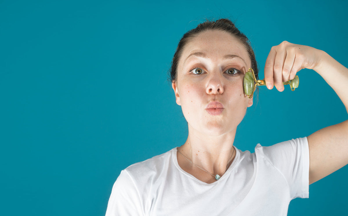 Femme utilisant un rouleau de jade sur les pommettes